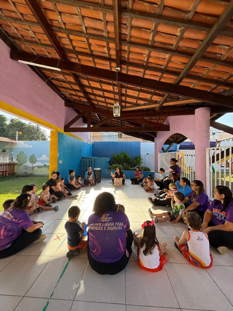 Educadoras e crianças em roda no pátio